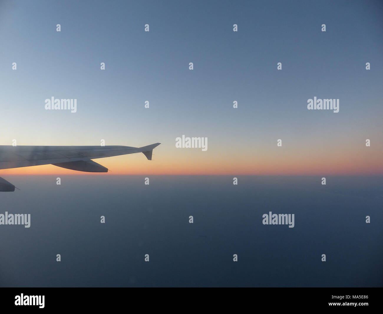 Ala de un Airbus 380 con el cielo iluminado por el sol naciente Foto de stock