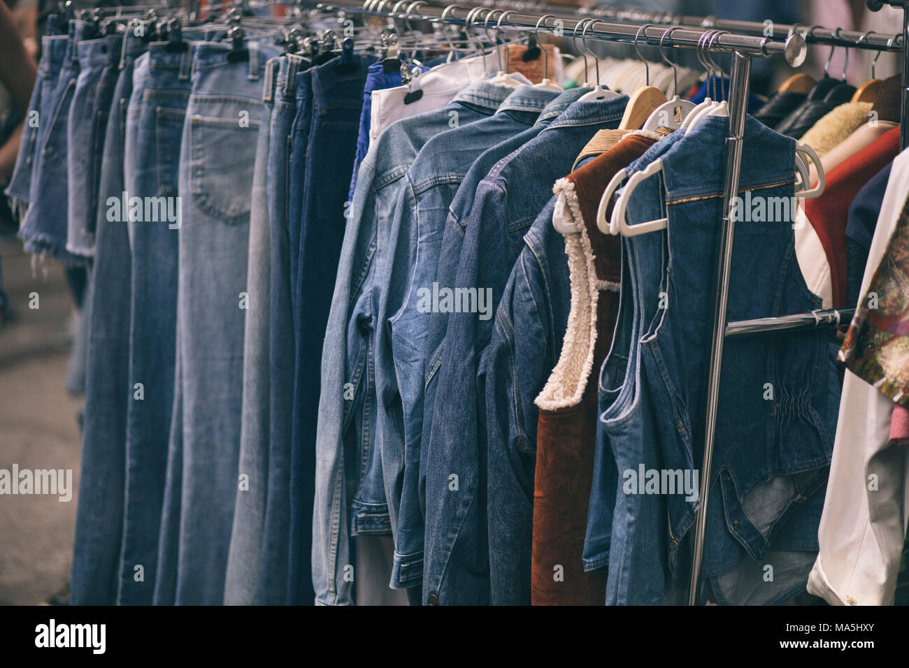 Montón de jeans colgados en un perchero Foto de stock