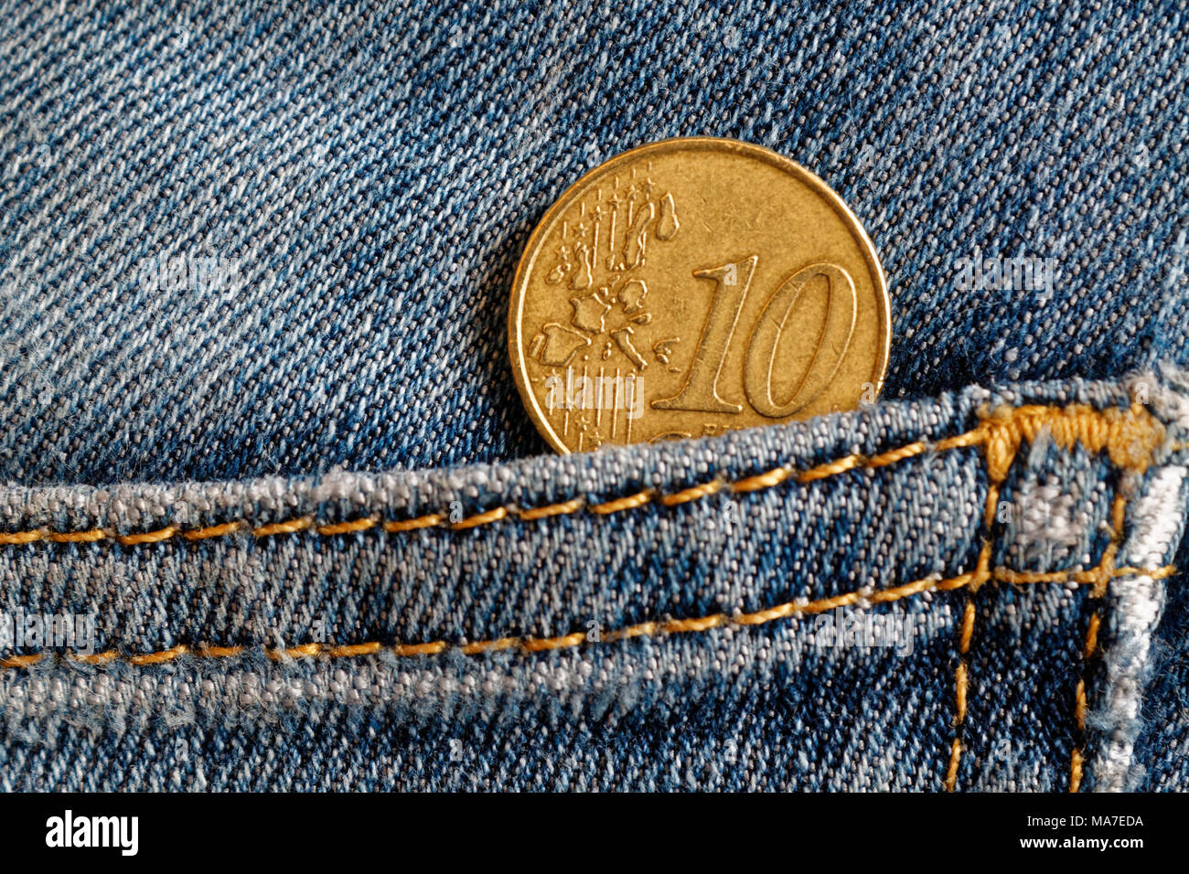 Monedas de euro con una denominación de 10 céntimos de euro en el bolsillo de los pantalones vaqueros azules desgastados Foto de stock