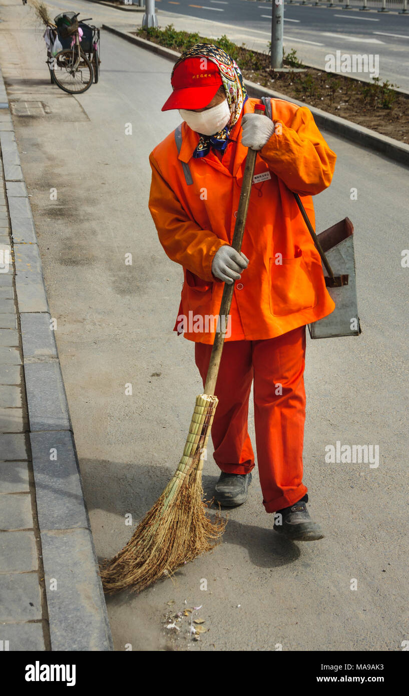Beijing, China - Abril 26, 2010: Primer plano de Street Sweeper en atuendo  naranja y blanco Mascarilla de boca en acción con twig escoba. La  recolección de basura triciclo en Fotografía de stock - Alamy