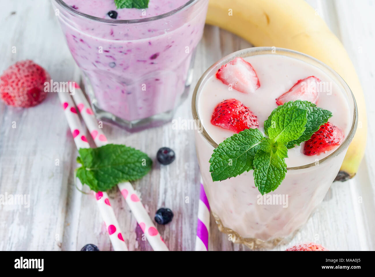 Dos de verano refrescante batido de color rosa y púrpura o batido con  menta, yogurt, arándanos y fresas. en cristal con ingredientes, sobre  blanco woode Fotografía de stock - Alamy