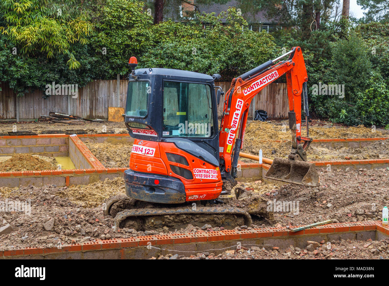 Hitachi naranja mecánica de maquinaria pesada excavadora en los cimientos de una nueva casa en construcción en una obra en construcción en Surrey, en el sudeste de Inglaterra, Reino Unido. Foto de stock