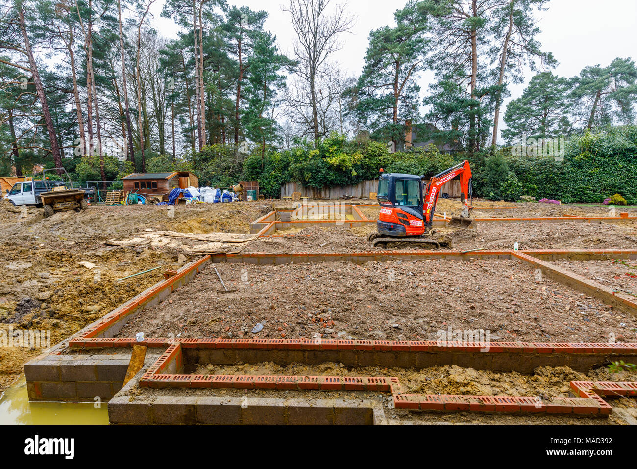 Hitachi naranja mecánica de maquinaria pesada excavadora en los cimientos de una nueva casa en construcción en una obra en construcción en Surrey, en el sudeste de Inglaterra, Reino Unido. Foto de stock