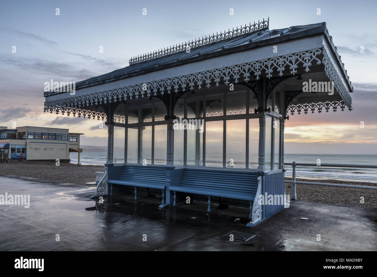 Un refugio con la Victorian Pier Bandstand en el fondo, el paseo marítimo y la playa de Weymouth, Weymouth, Dorset, Inglaterra, Reino Unido. Foto de stock