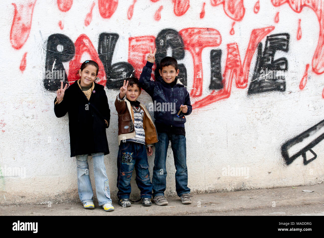Bilin, Palestina, Diciembre 31, 2010: Los niños palestinos están de pie en la calle de Bilin delante de "sangriento" palestina graffiti. Foto de stock