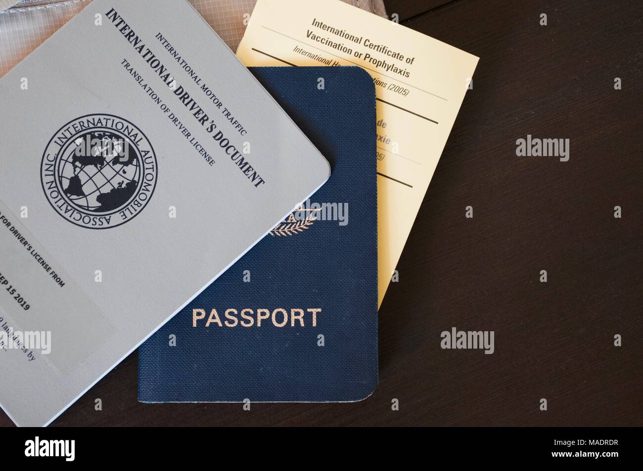 Documentos de viaje internacionales incluyendo pasaporte, certificado amarillo de la vacunación de la fiebre del libro y licencia de conducir internacional sobre un fondo de madera Foto de stock