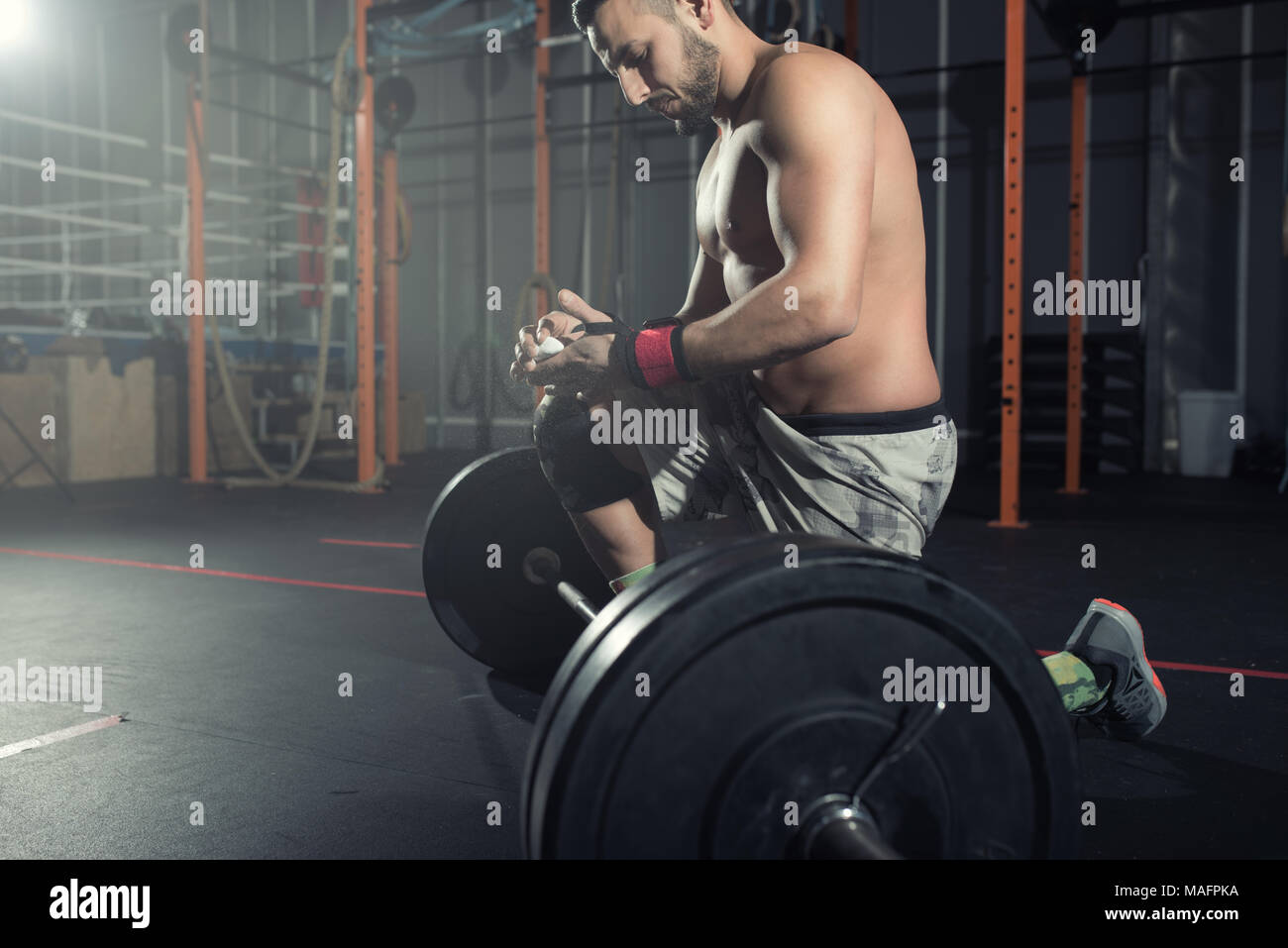 Athletic hombre realiza en el gimnasio con un barbell Foto de stock