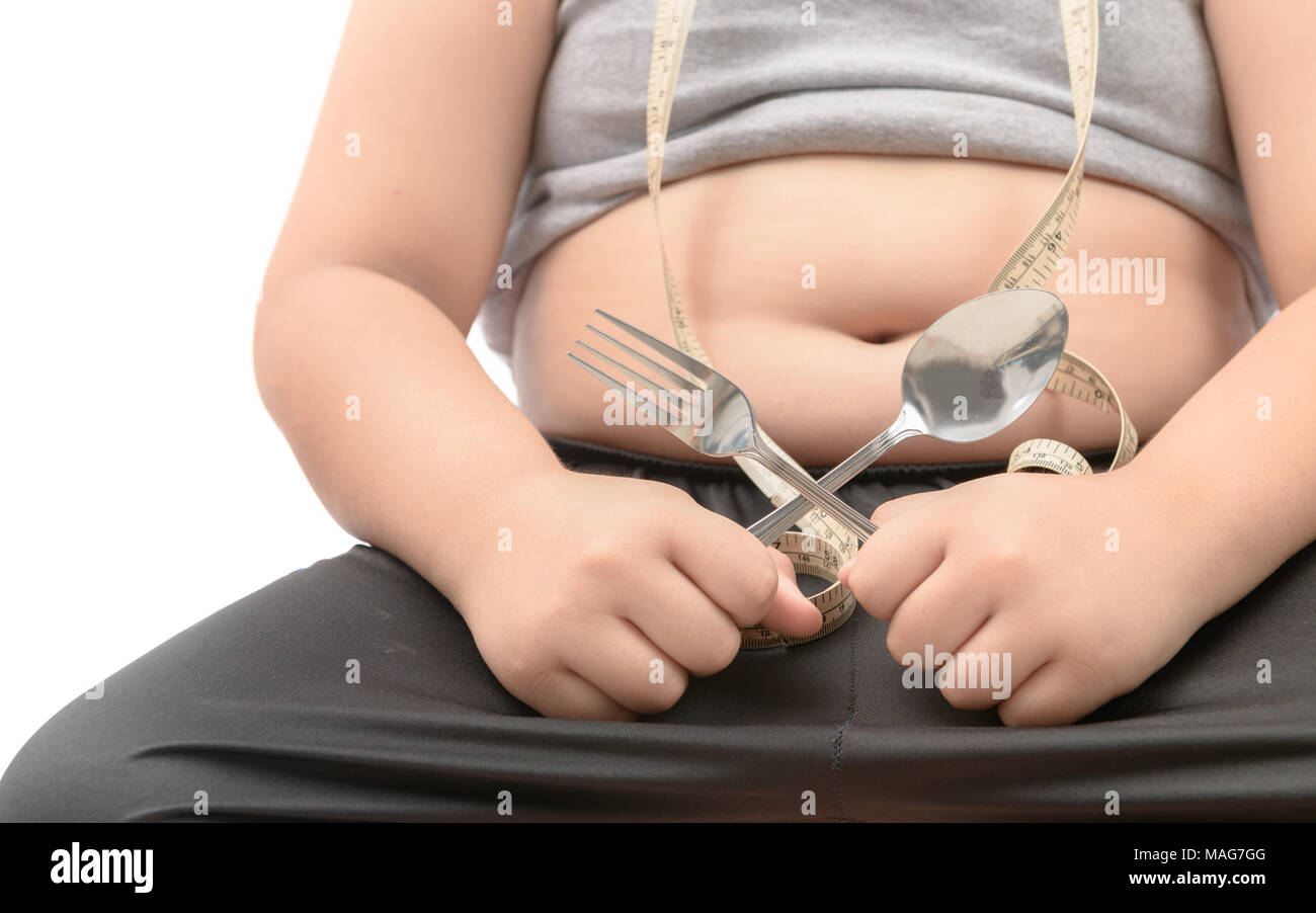 Obeso Fat Boy holding tenedor y cuchara aislado sobre blanco, dieta para perder peso y concepto saludable Foto de stock