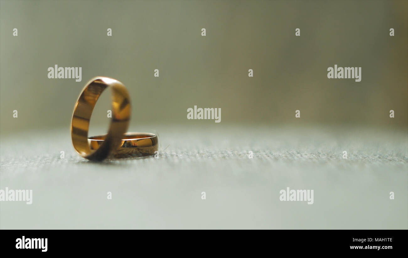 Un anillo de bodas de oro laminado para otro. Vídeo. Anillos de boda. Utiliza dos anillos de boda de oro sobre fondo gris. Cierre joya nupcial del matrimonio. Foto de stock