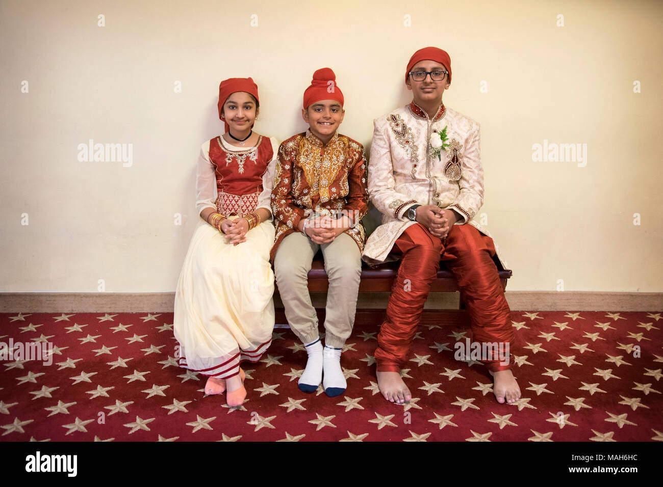 Tres adolescentes invitados a la boda en coloridos trajes étnicos en el Centro Cultural sij en Richmond Hill, Queens, Nueva York. Foto de stock