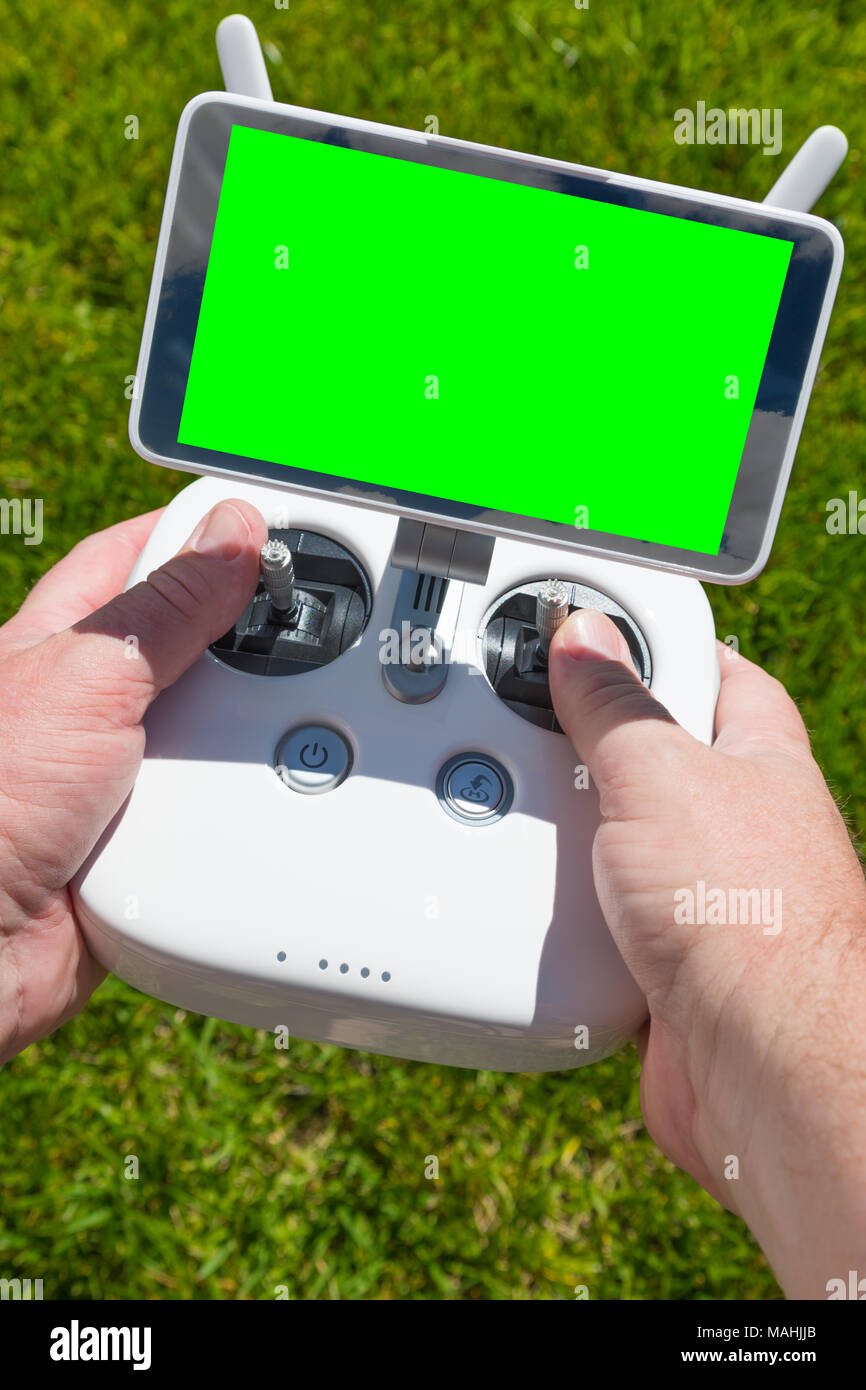 Manos sosteniendo Drone Quadcopter Controlador con pantalla verde en blanco. Foto de stock