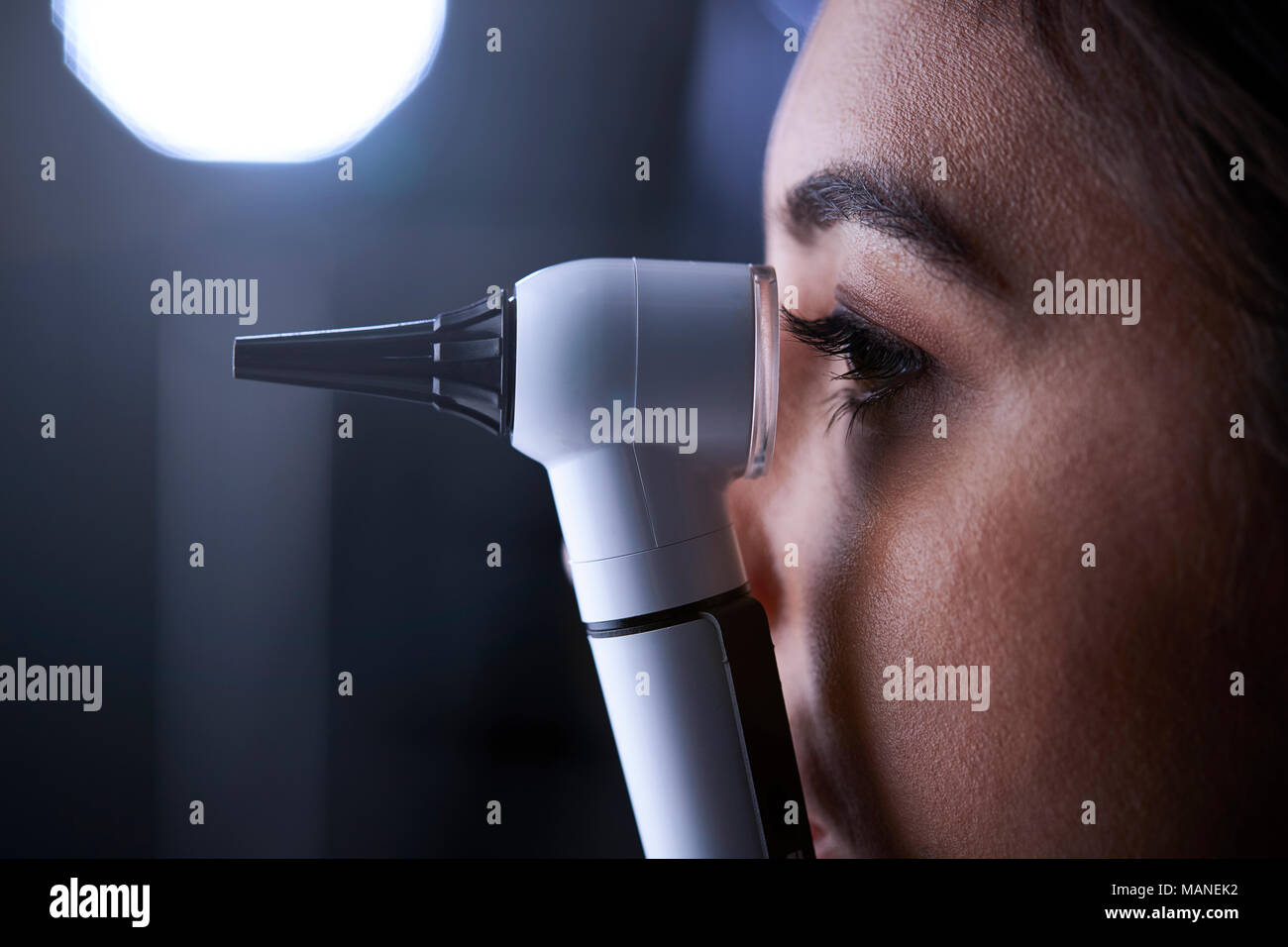 Doctora mediante otoscopio para examen, vista lateral Foto de stock