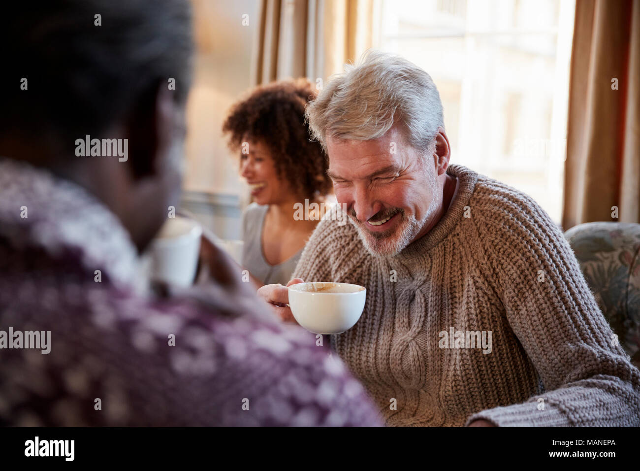 Un varón de mediana edad reunión de amigos en torno a una mesa en la cafetería. Foto de stock