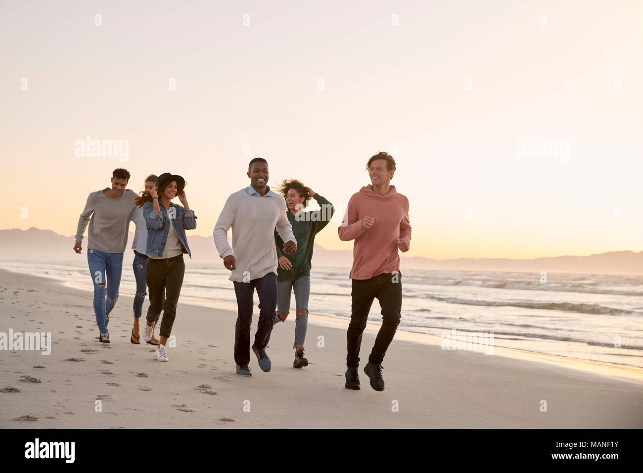 Grupo de Amigos caminando por la playa en invierno juntos Foto de stock