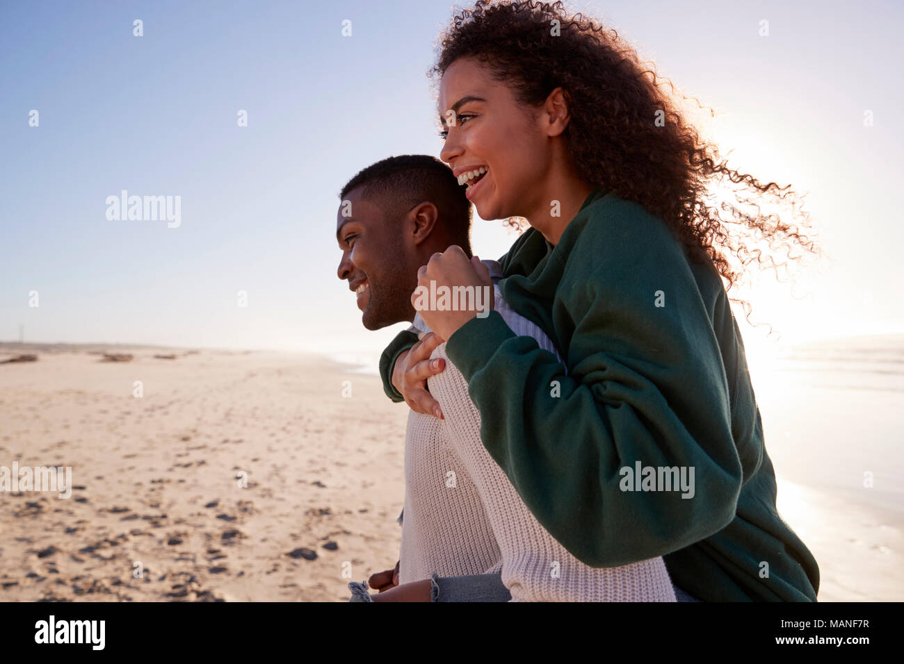 Hombre Mujer dando Piggyback en invierno vacaciones de playa Foto de stock