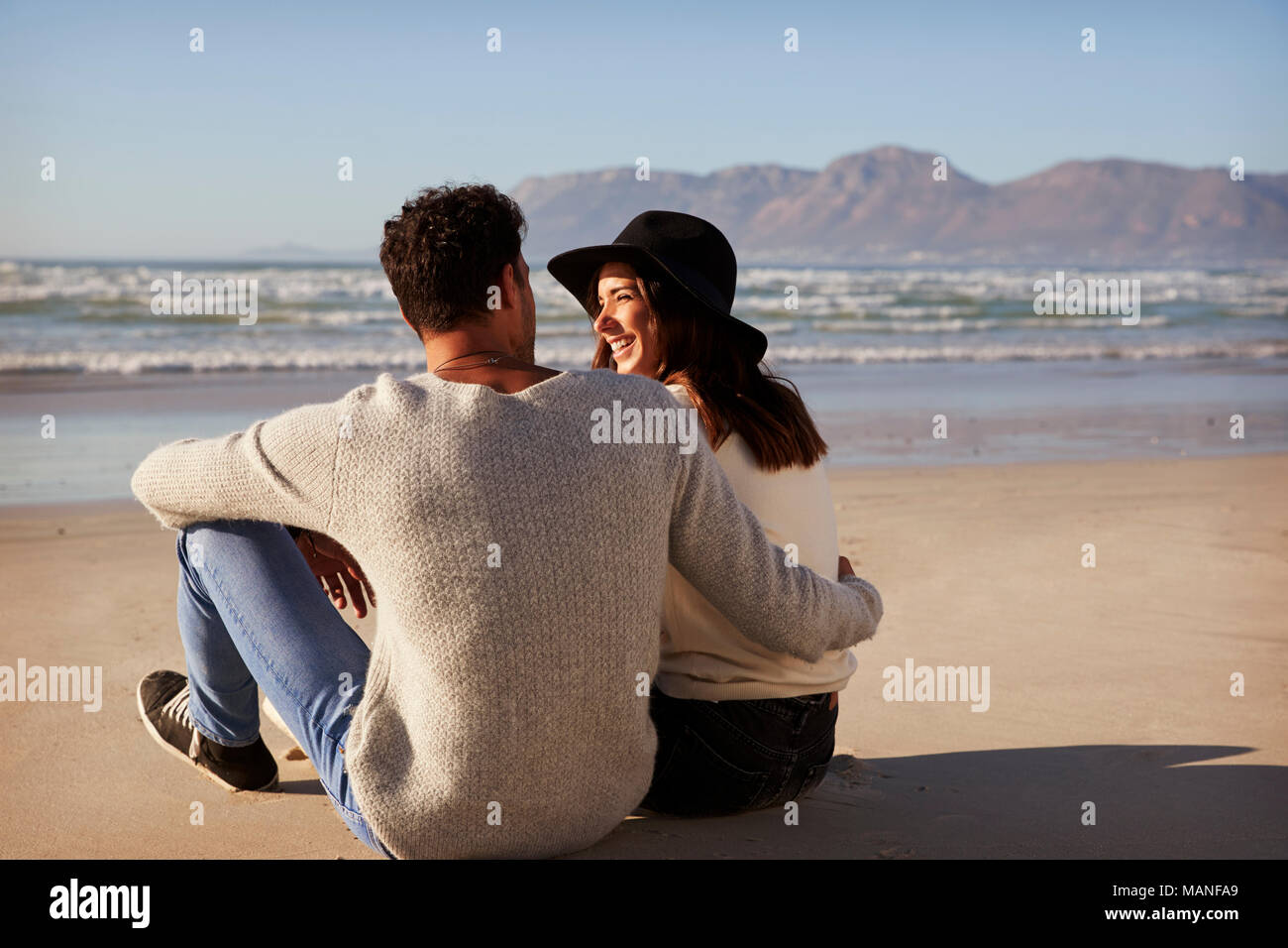 Pareja romántica sentado en la playa de invierno juntos Foto de stock
