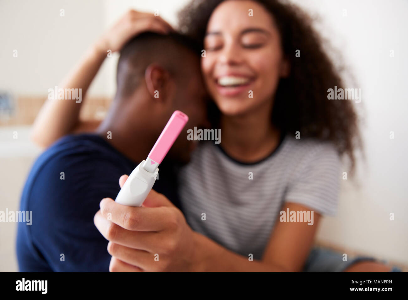 Pareja celebrando el positivo resultado de la prueba de embarazo en casa Foto de stock