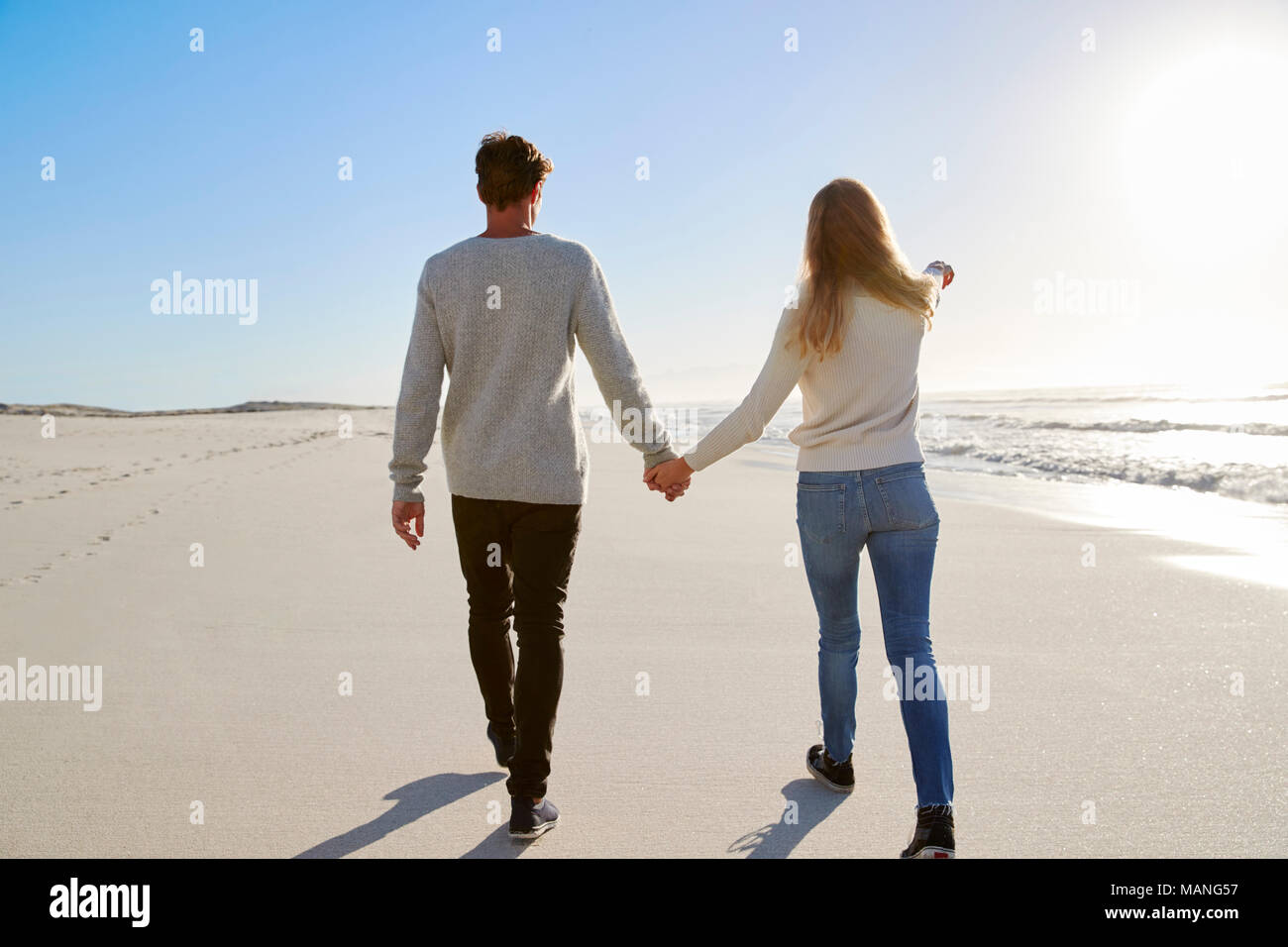 Vista trasera de la pareja enamorada caminando por la playa de invierno juntos Foto de stock