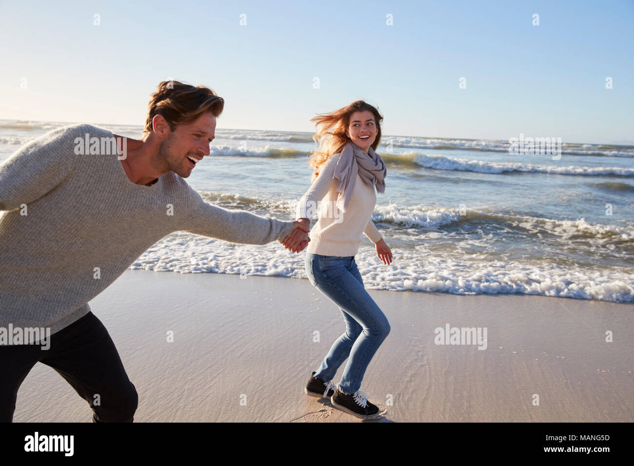Par Divertirse corriendo por la playa de invierno juntos Foto de stock