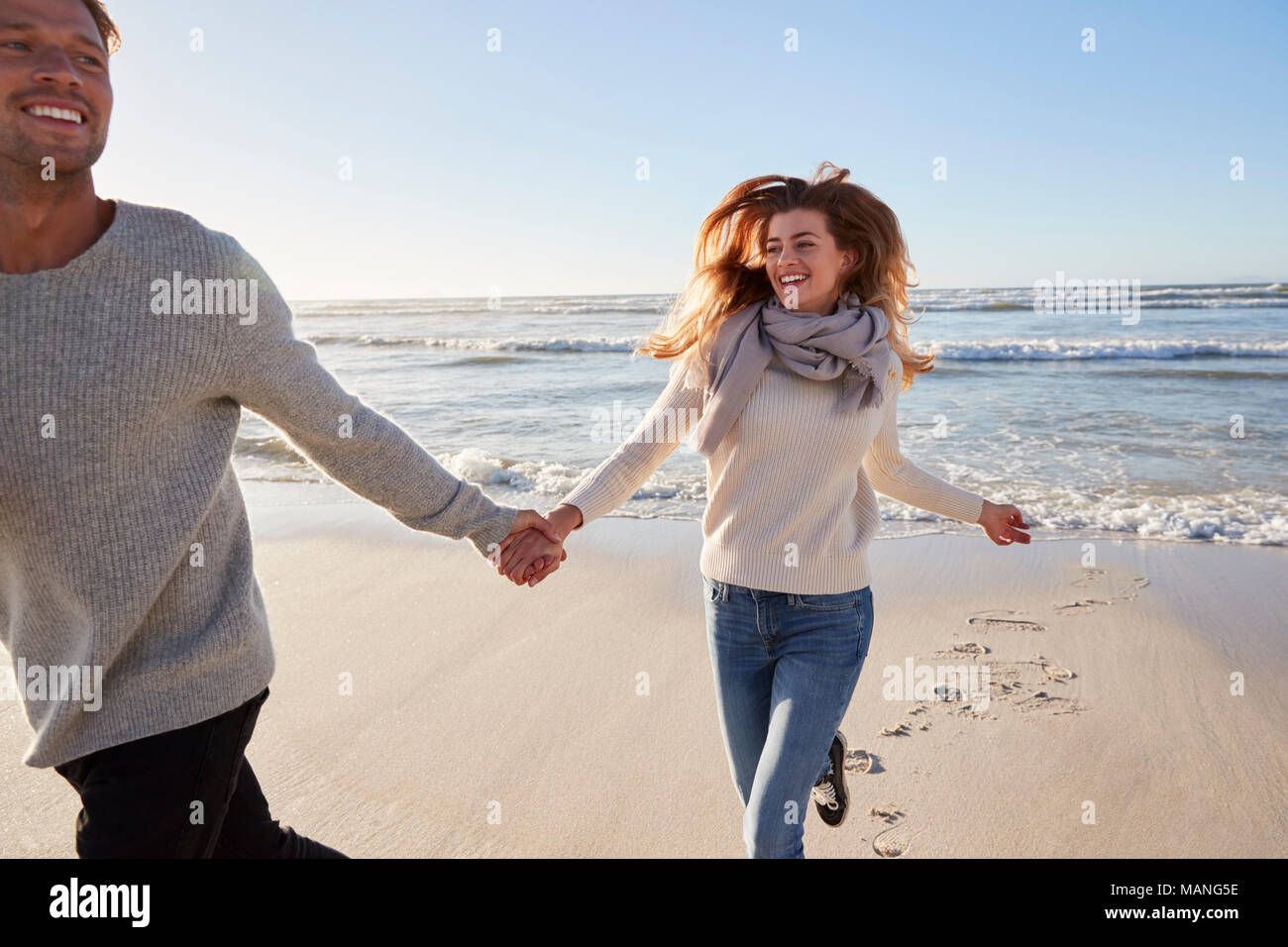 Par Divertirse corriendo por la playa de invierno juntos Foto de stock