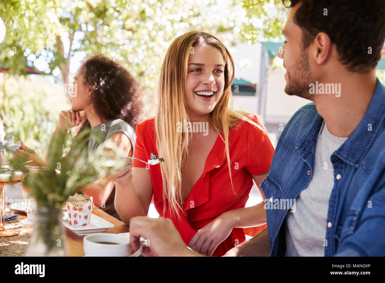 Tres jóvenes amigos adultos en una mesa de comedor al aire libre Foto de stock