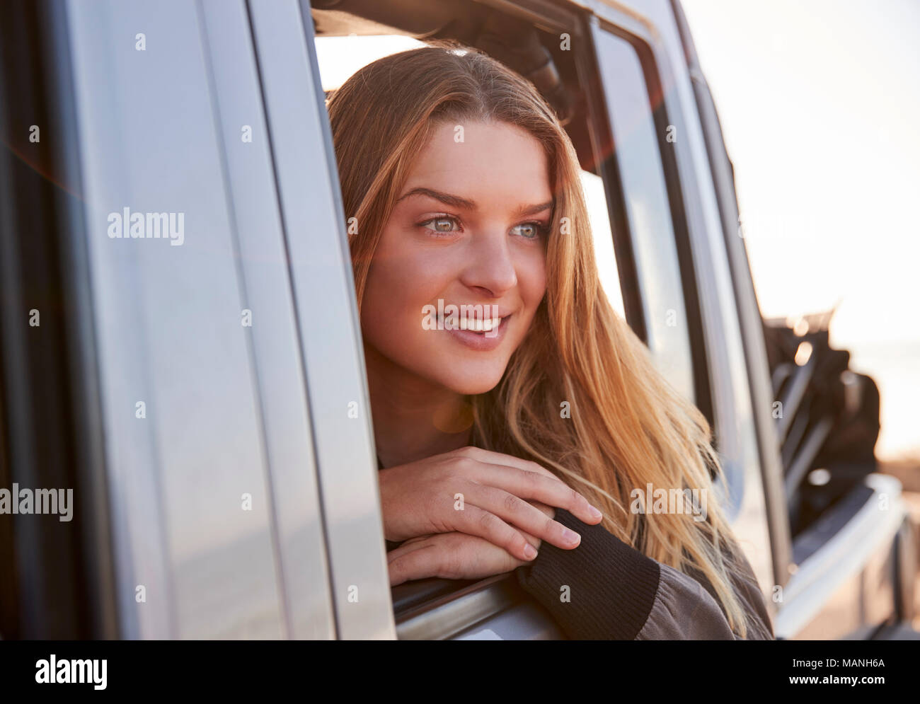 Mujer joven en busca de abrir la ventana del pasajero de un coche Foto de stock