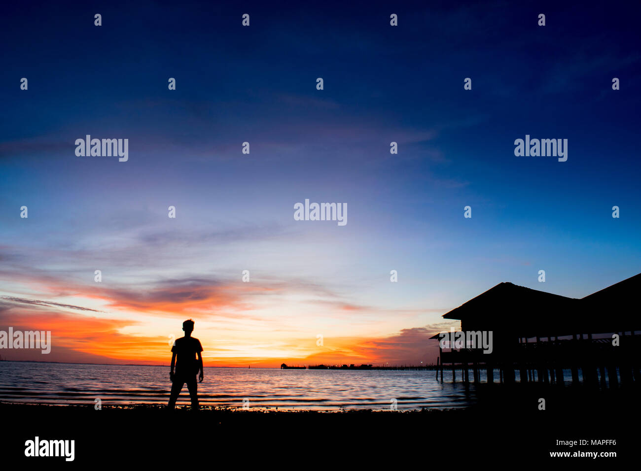 Silueta hombre en la playa contra el ocaso - La isla de Bintan, Indonesia Foto de stock