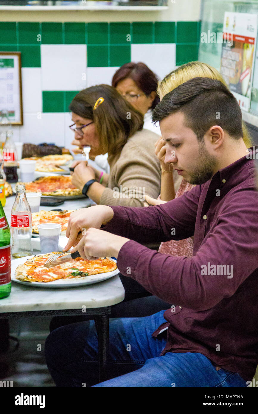 Gente comiendo pizza en el famoso restaurante L'Antica Pizzeria Da Michele en Nápoles, Italia Foto de stock
