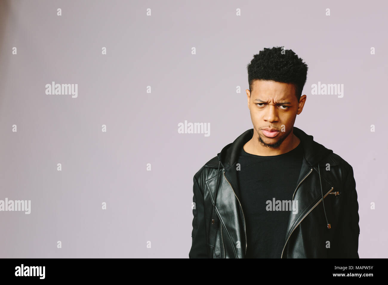 Retrato de un joven enojado y deprimido, aislado sobre fondo studio Foto de stock