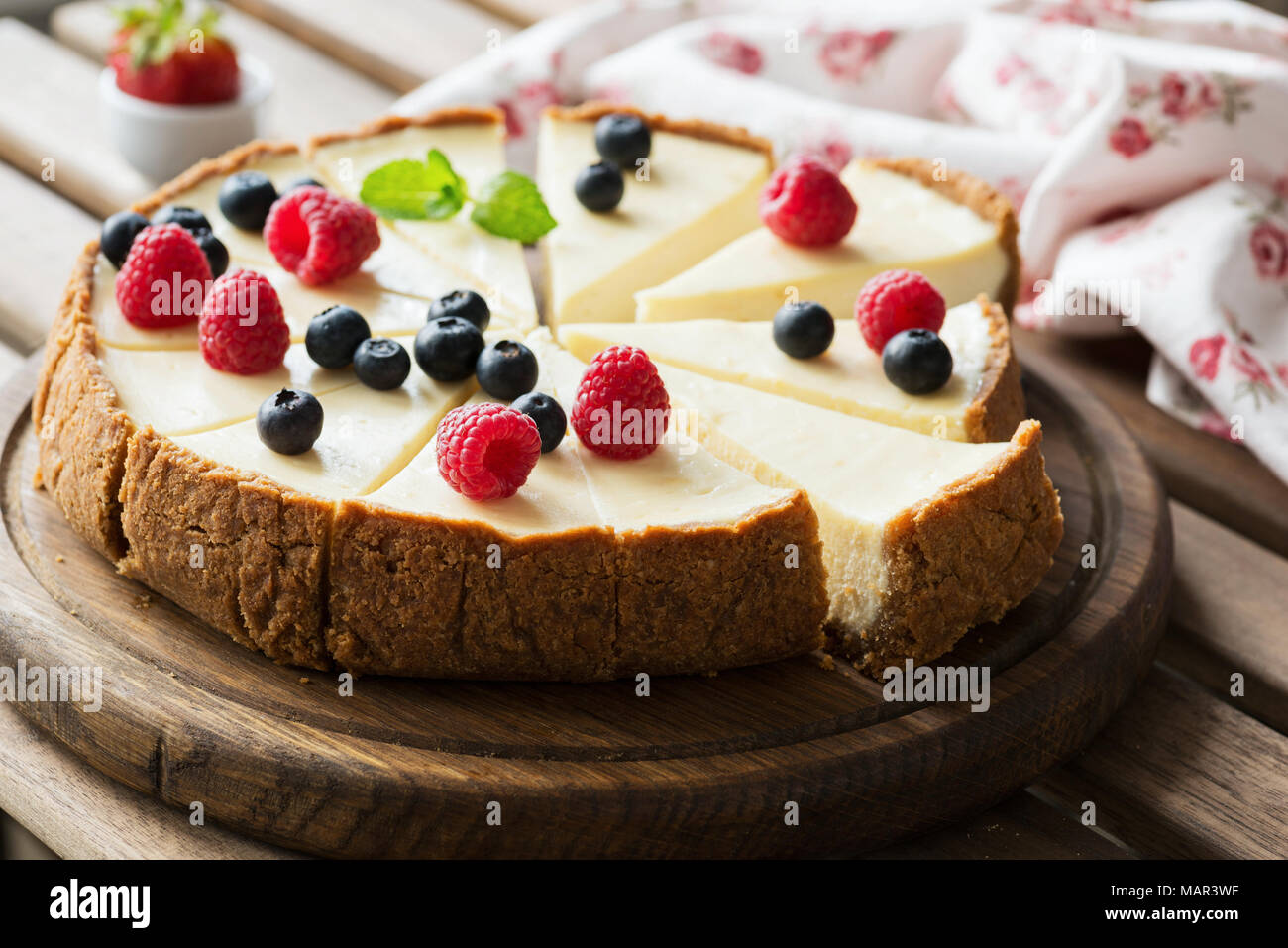 Cheesecake clásico con bayas frescas sobre placa de madera, el enfoque selectivo, composición horizontal Foto de stock