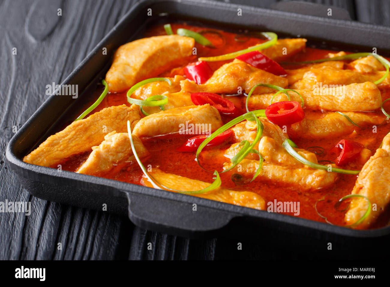 Pollo con curry panang chili pepper closeup en chapa negra horizontal sobre la mesa. Foto de stock