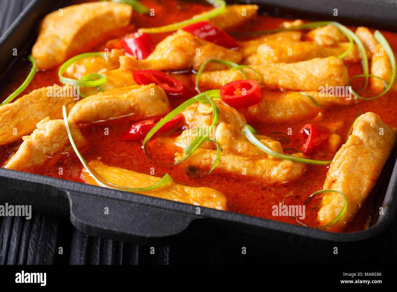 Delicioso pollo picante curry panang cerca en una placa negra horizontal sobre la mesa. Foto de stock