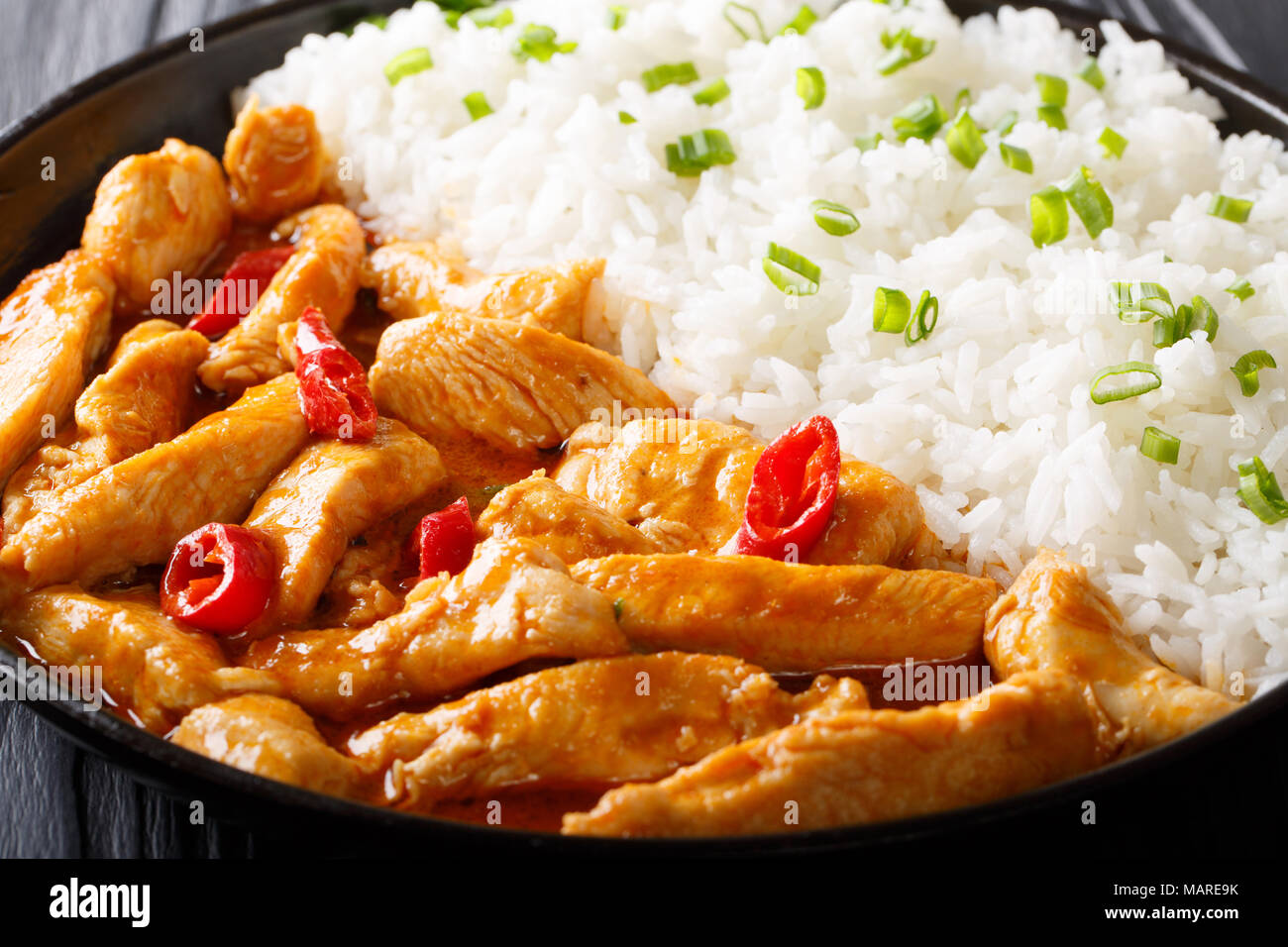 Curry panang de pollo con guarnición de arroz cerca en una placa horizontal. Foto de stock