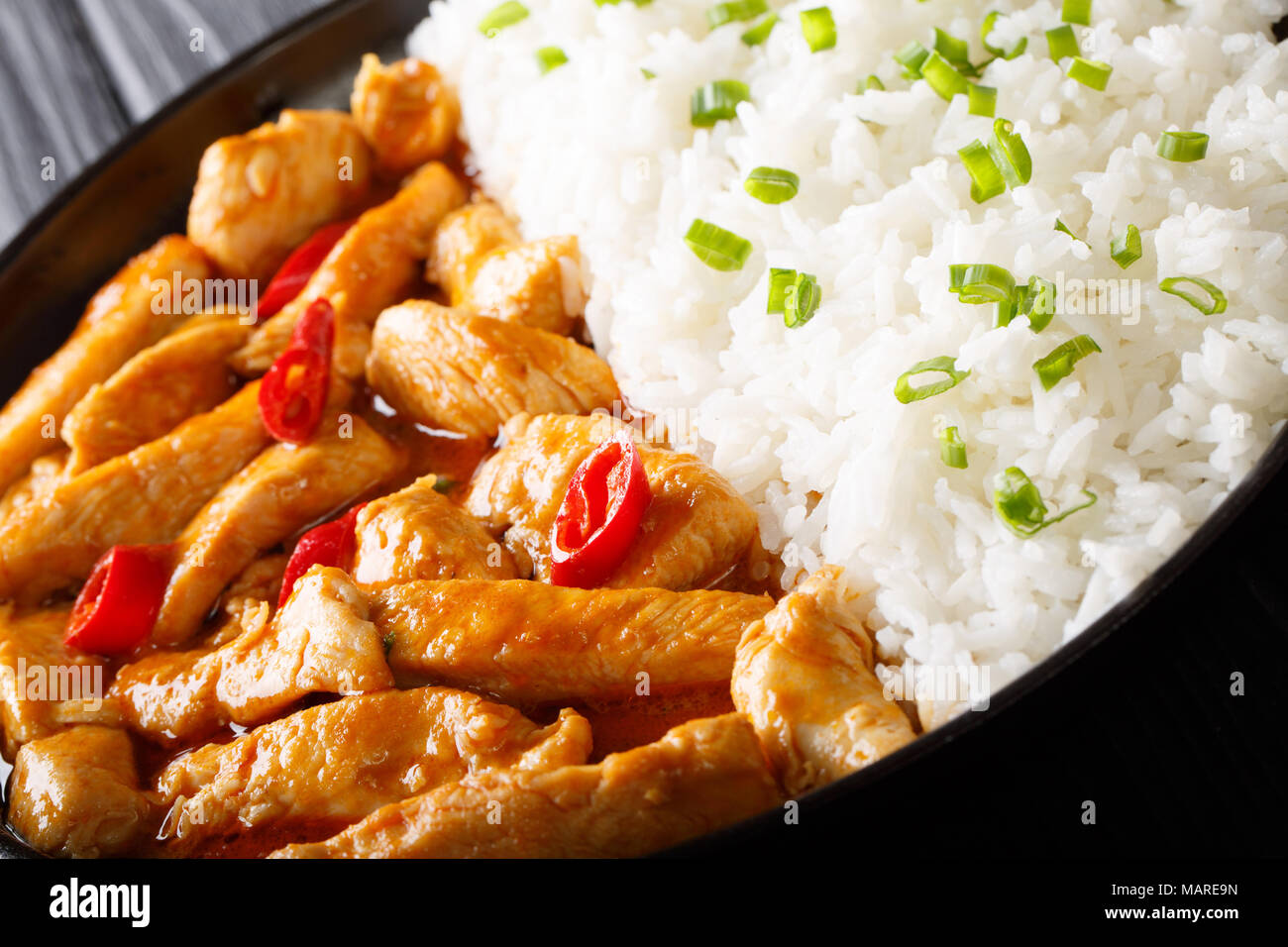 Curry panang de Pollo casero picante con arroz y cebolla verde cerca en una placa horizontal. Foto de stock