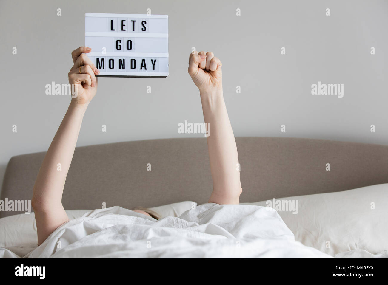 Mujeres en la cama bajo las sábanas sosteniendo una Lets go lunes firman  Fotografía de stock - Alamy