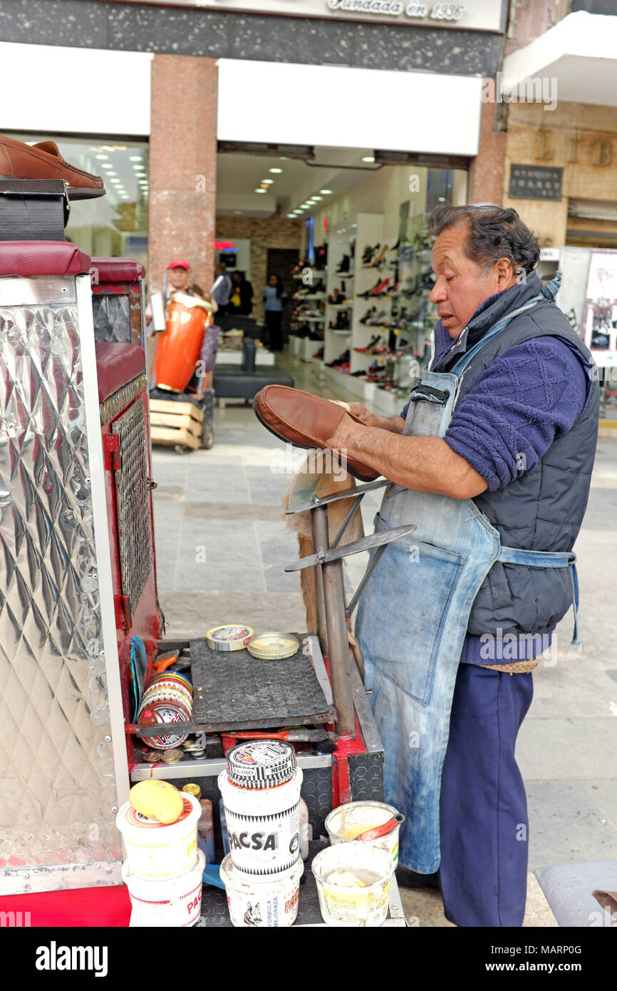 Un lustrabotas de pie en una acera en la Ciudad de México, México, proporciona ingresos y ocupación para el hombre luciendo los zapatos. Foto de stock