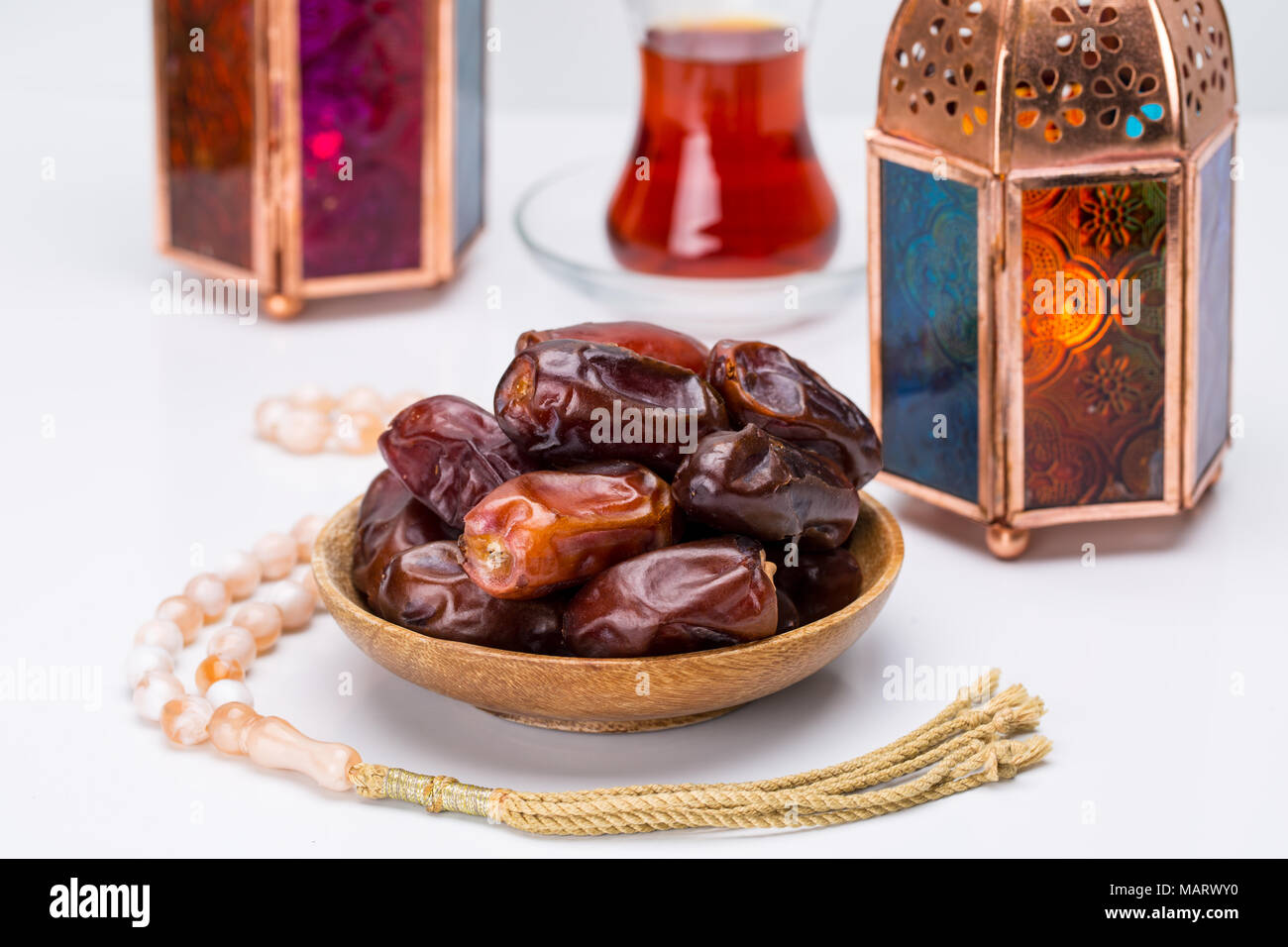 Ramadan Kareem festiva, cerca de fechas en placa de madera y Rosario con linternas y lámparas orientales taza de té negro sobre fondo blanco. Días festivos islámicos Foto de stock