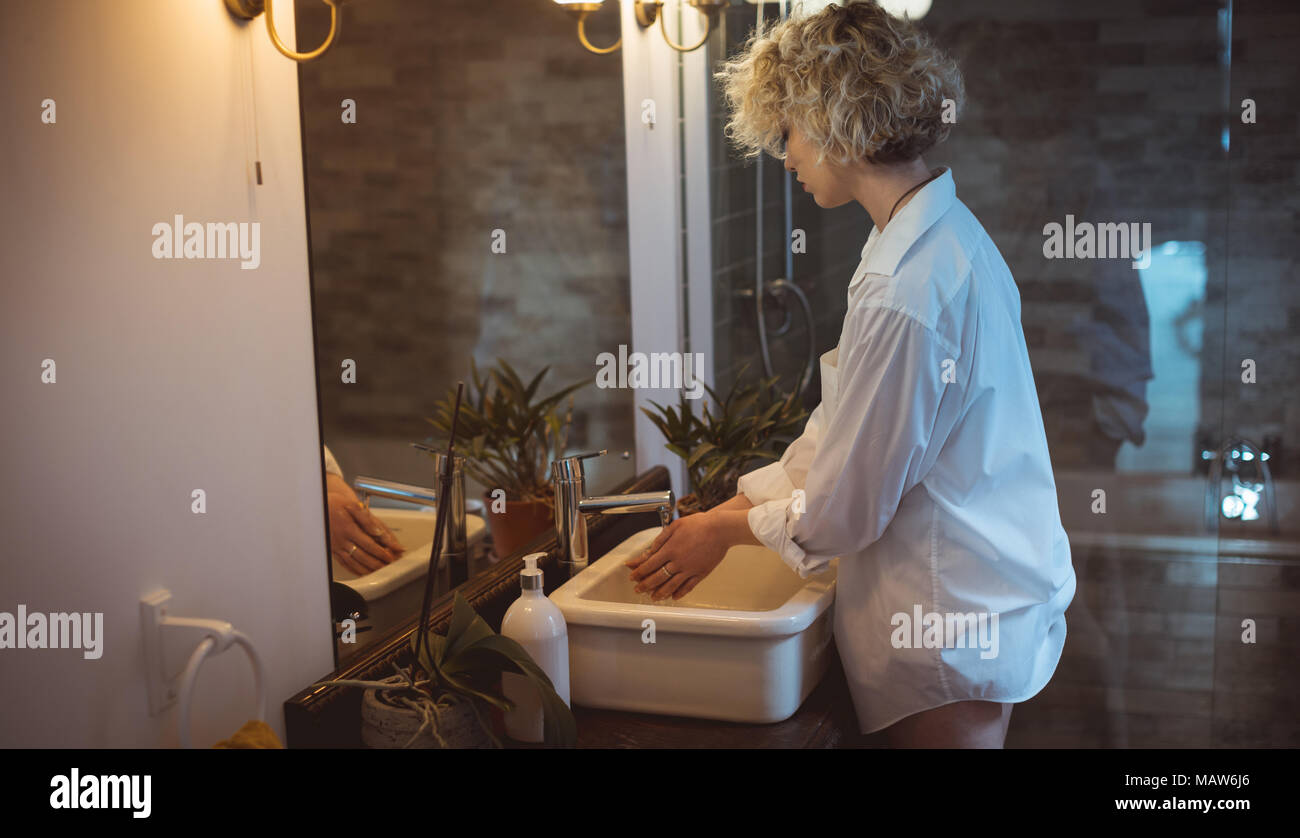 Mujer lava su mano en el baño. Foto de stock