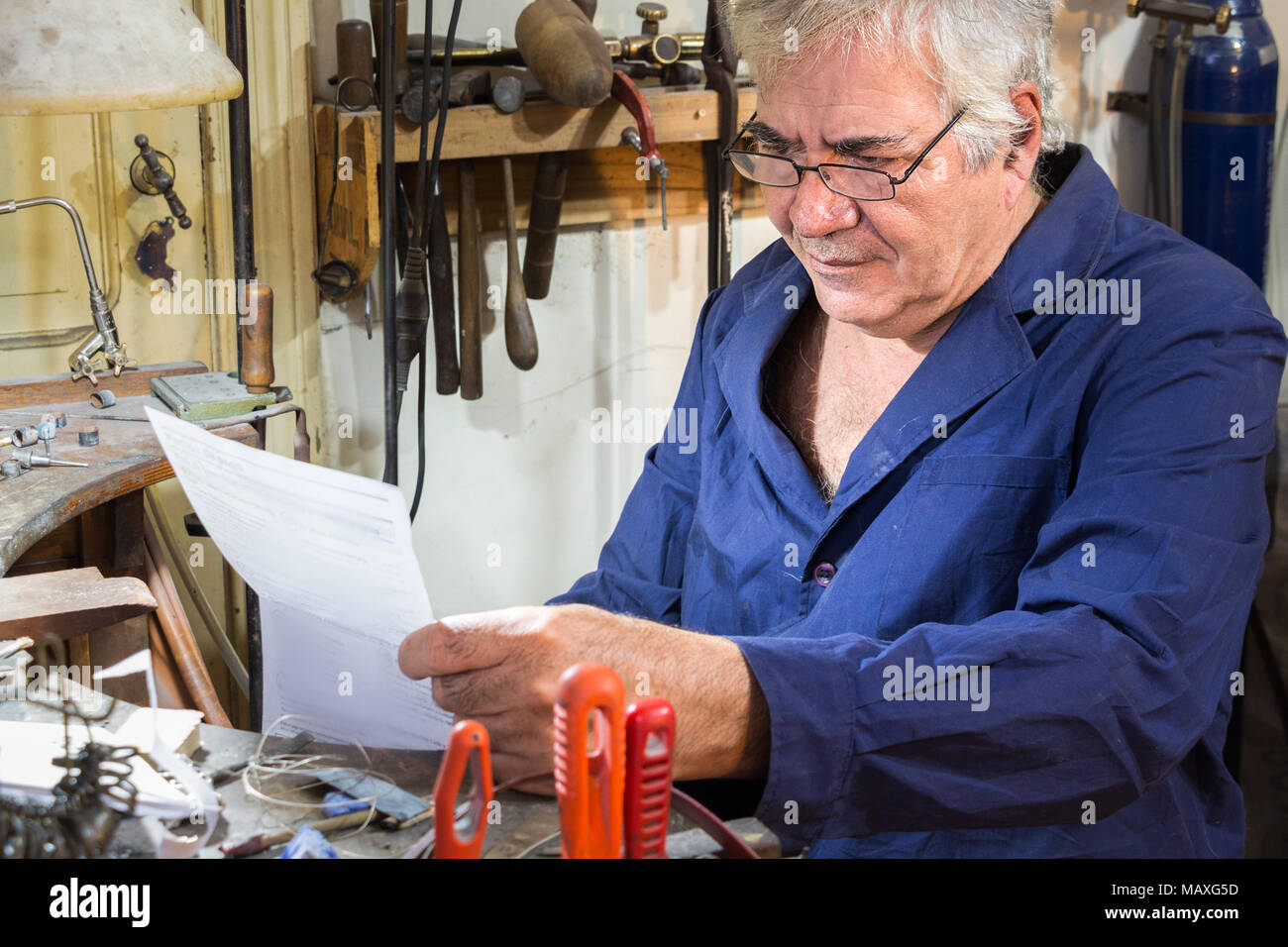 Un trabajador está estudiando un proyecto de ley en su taller de joyería, se preocupe, interesados. Foto de stock