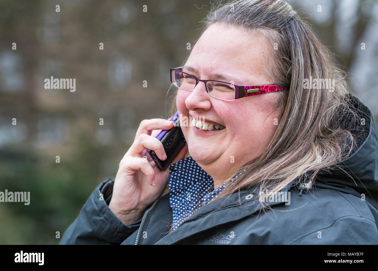 Mujer joven sonriente y feliz mientras buscan hablando por un teléfono móvil. Concepto de felicidad. Gratas noticias. Noticias felices. Foto de stock