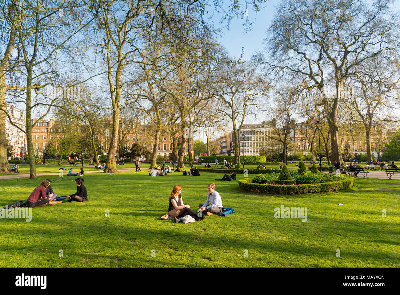 Gente sentada en la hierba en Russell Square, Bloomsbury, Londres, Reino Unido. Foto de stock