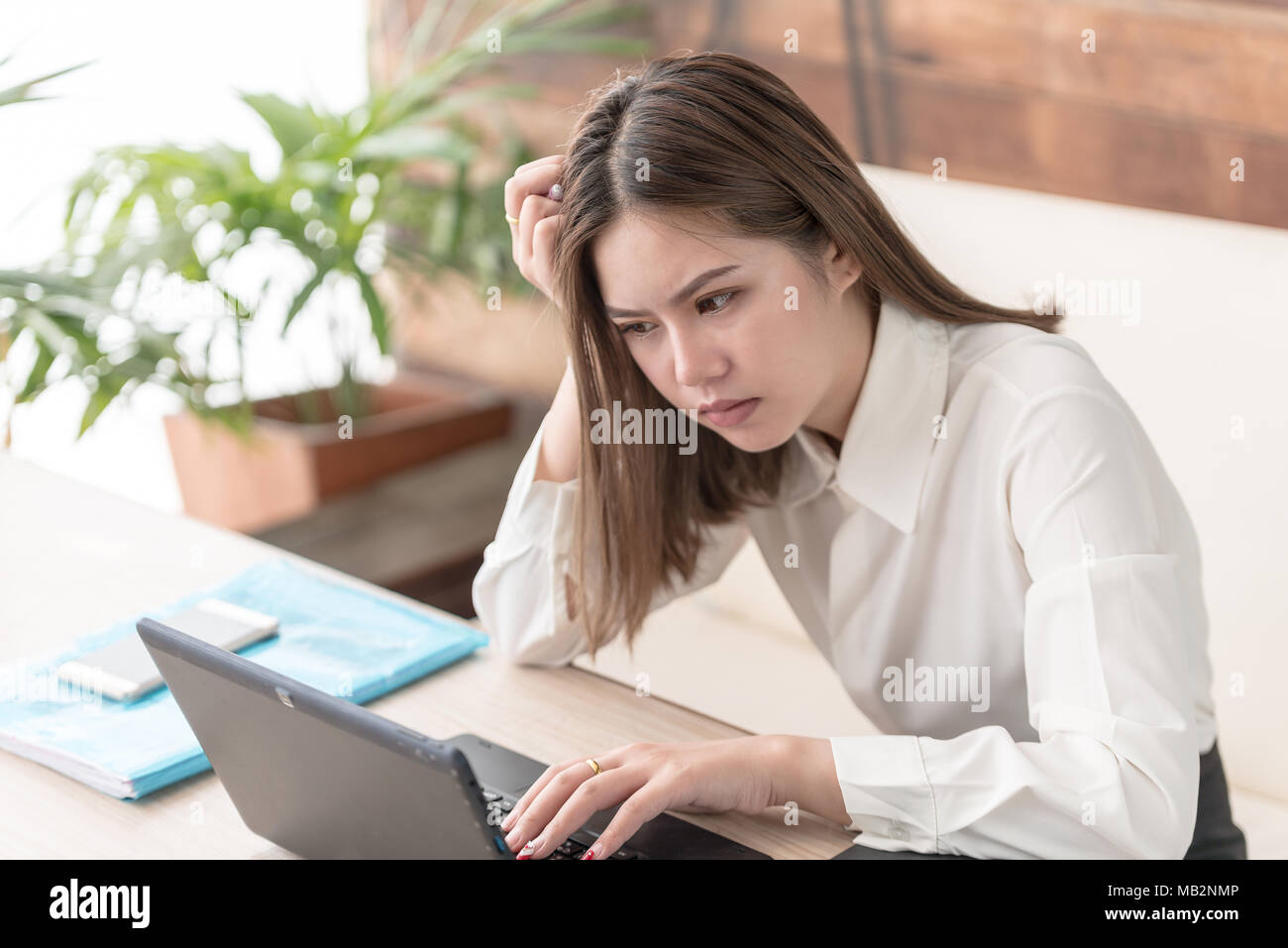 Mujer Asiática de negocios trabajando en equipo y leyendo la información requerida sobre el portátil,secretaria parezca grave y destacó con ella Foto de stock