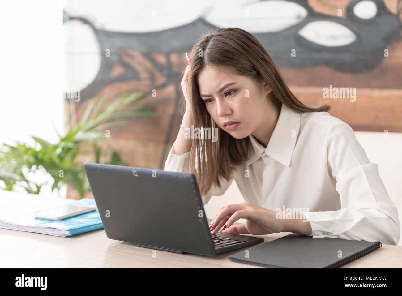 Mujer Asiática de negocios trabajando en equipo y leyendo la información requerida sobre el portátil,secretaria parezca grave y destacó con ella Foto de stock