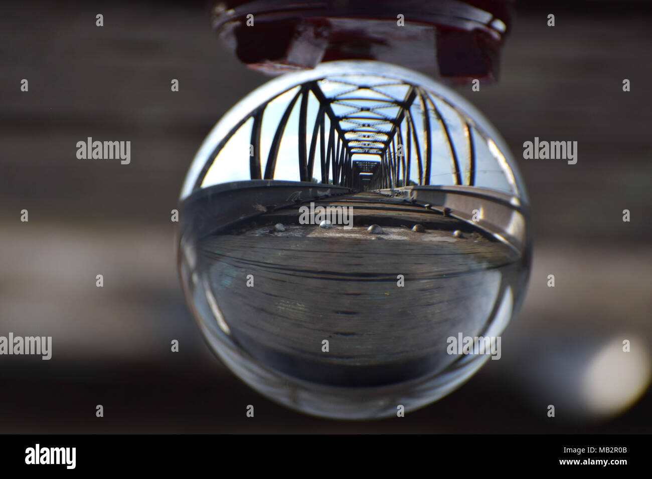 Una vía de ferrocarril y el puente vistos a través de una bola de cristal. Una metáfora visual para la visión, moviéndose hacia adelante mientras se aloja en la vía y el cruce de puentes. Foto de stock