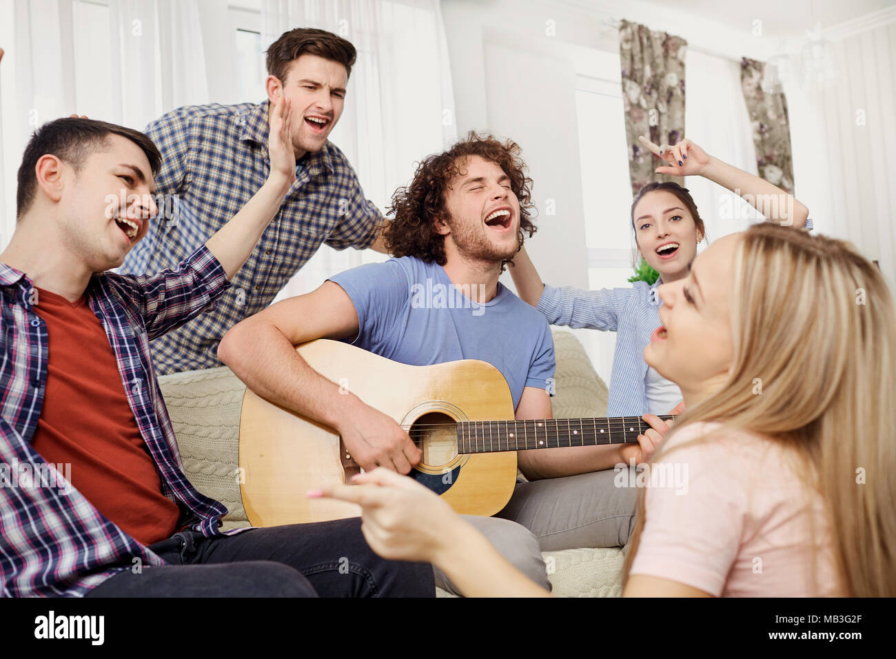 Un grupo de amigos con una guitarra cantando canciones divertidas en la  parte interior Fotografía de stock - Alamy
