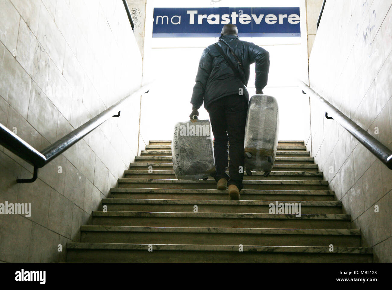 Subir las escaleras de pasajeros con su equipaje en la estación de tren Trastevere, Roma, Italia Foto de stock