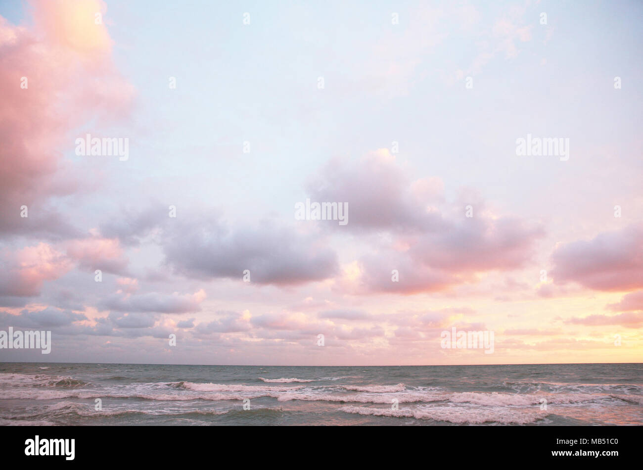 Puesta de sol en el mar con nubes rosa Foto de stock