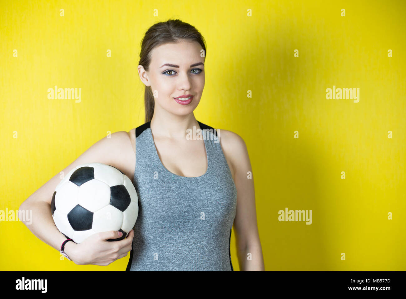Una hermosa chica en un traje deportivo gris sonríe y sostiene un balón de  fútbol Fotografía de stock - Alamy