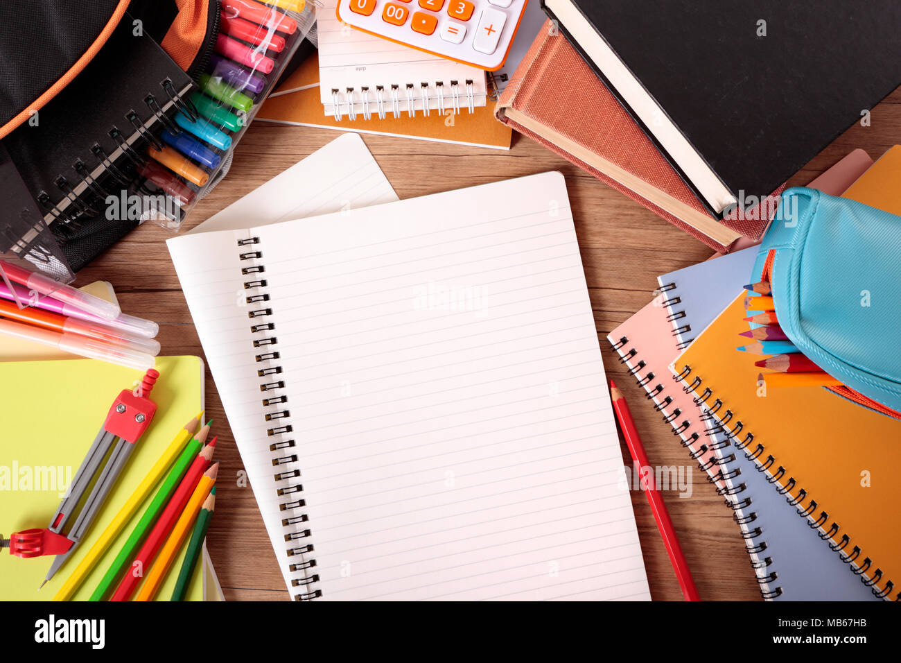 Escritorio del alumno ocupado con bloc de notas abierto, bolsa escolar,  libros de texto y varios lápices y lápices de colores Fotografía de stock -  Alamy