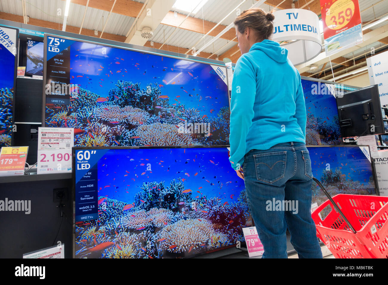 Mujer mirando su nuevo televisor de alta definición 4k pantallas en almacén eléctrico Foto de stock